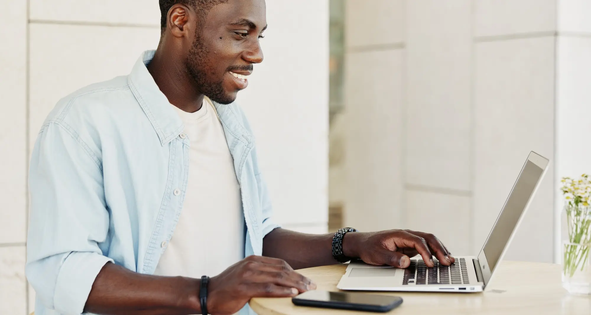 un homme souriant en train de travailler sur son ordinateur